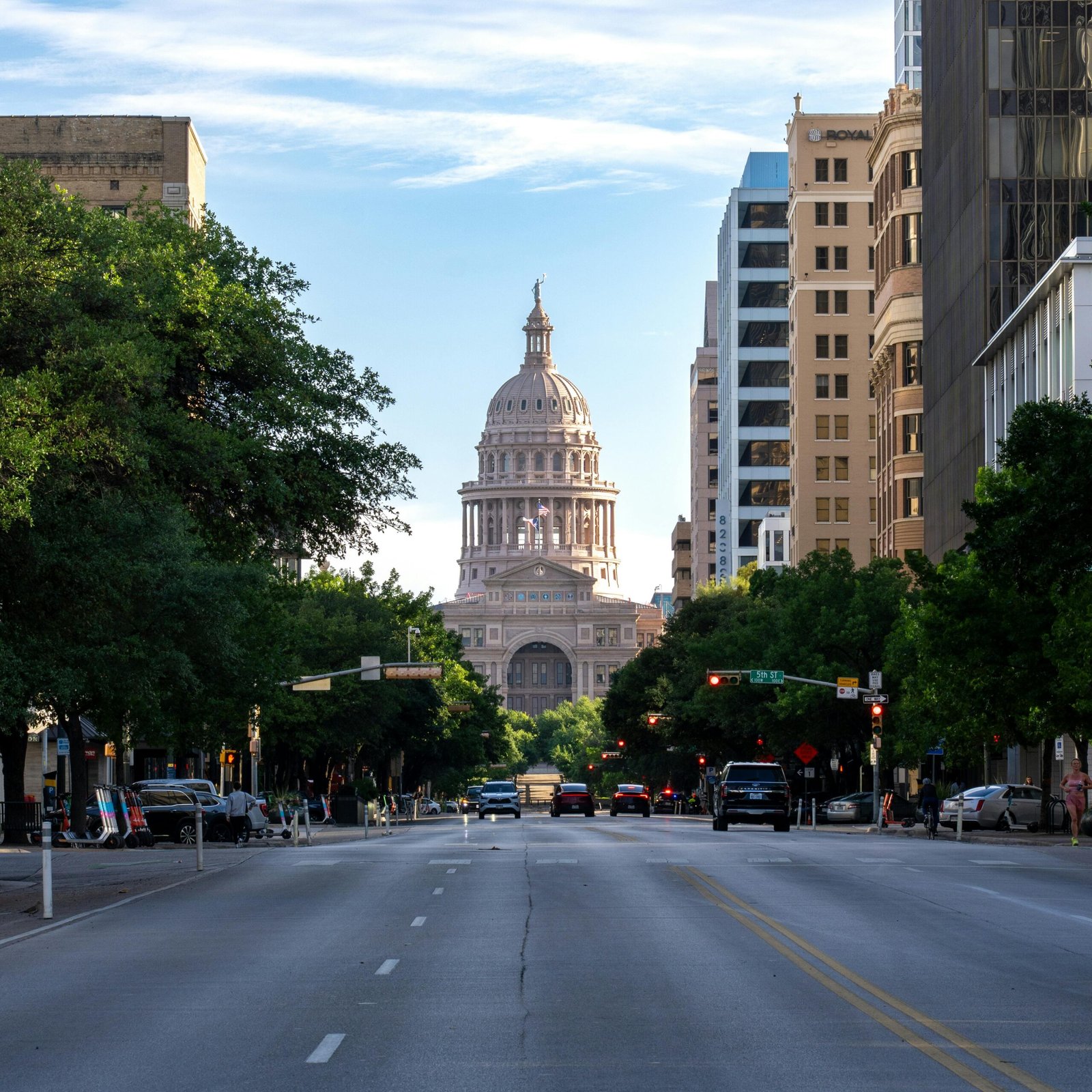 View of the Texas State Capitol in Austin with a clear sky and surrounding skyscrapers.
